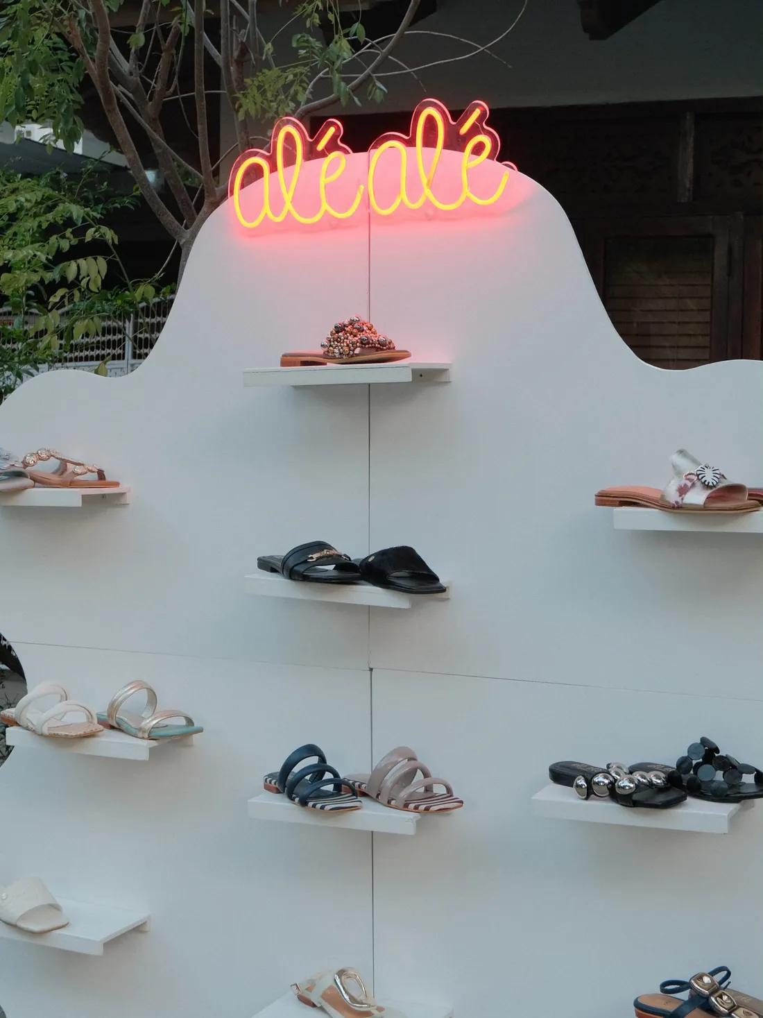 Pared del showroom de Alé Alé con el letrero de neón y sandalias en exhibición